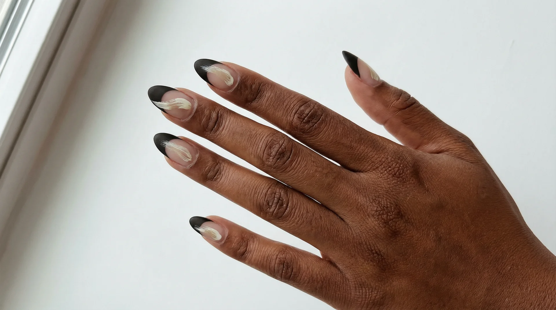 Almond nails with black french tip and single abstract gestural brushstroke on nail body