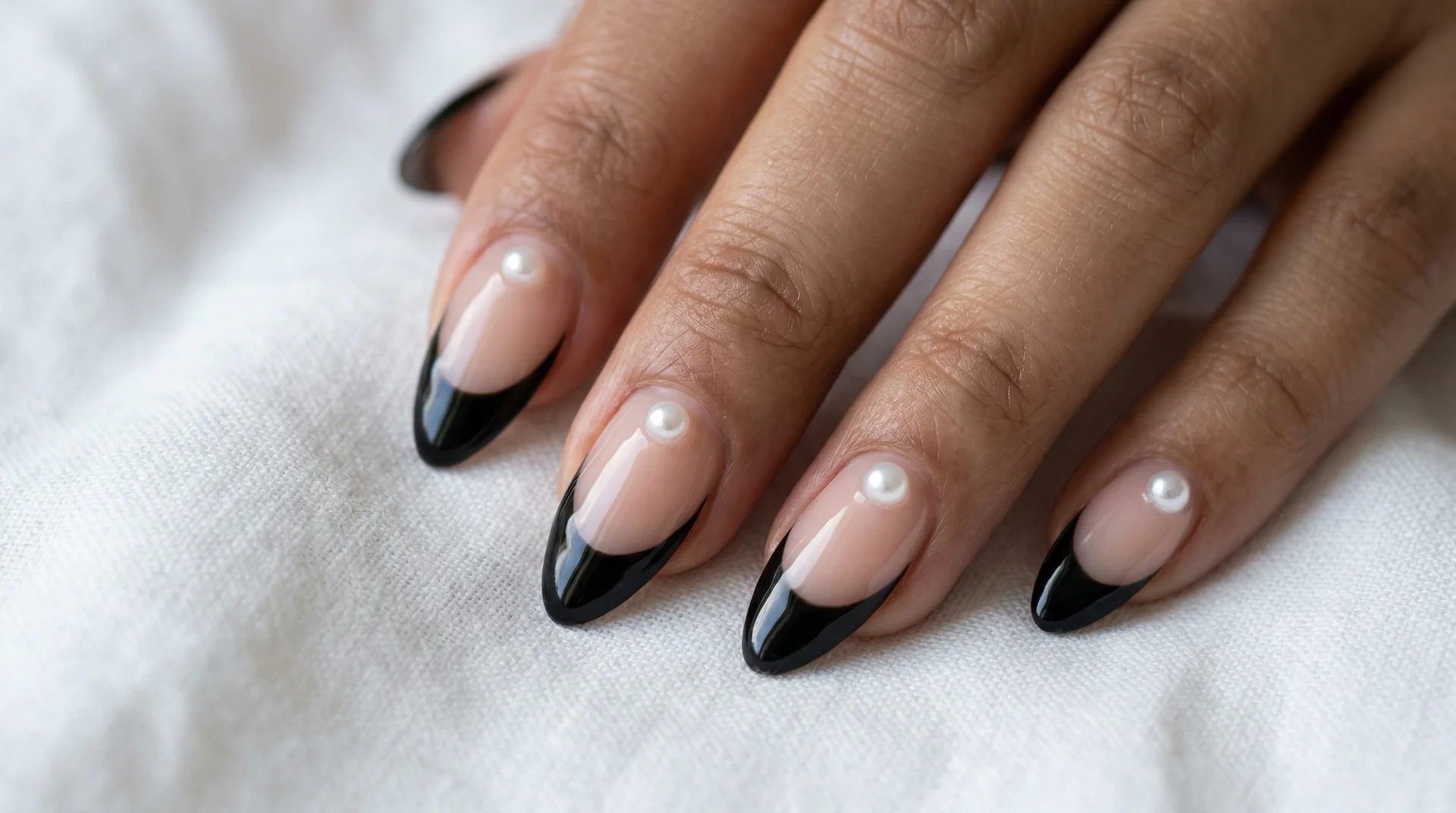 Almond nails with black french tip and tiny micro pearls placed at the base