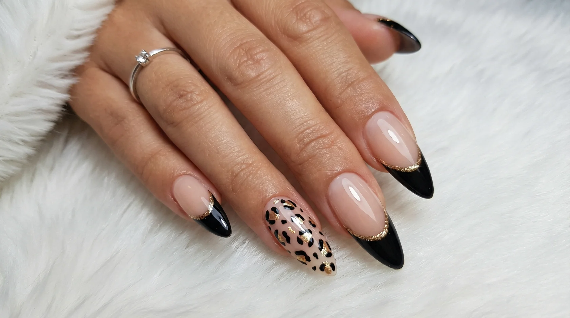 Almond nails with black tip, gold liner, and leopard print accent nails on nude base