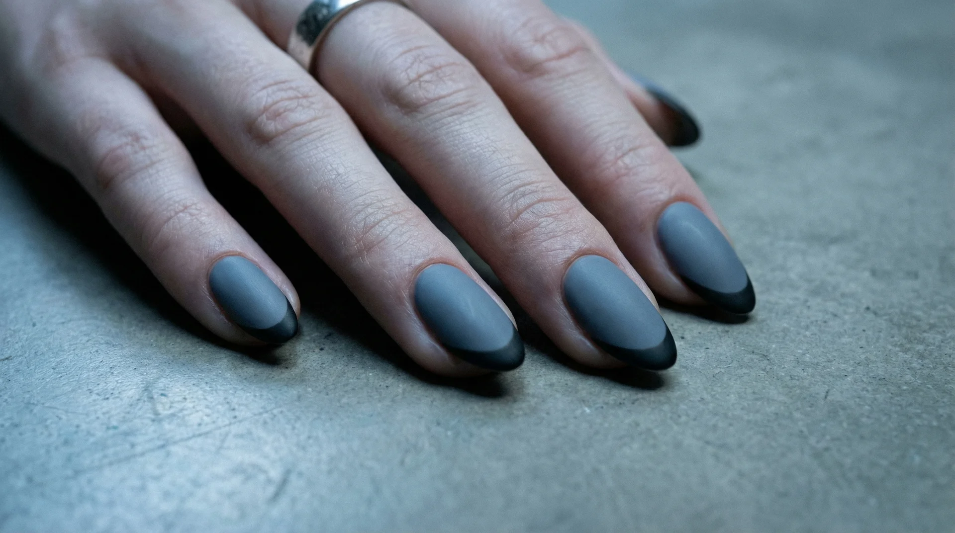 Almond nails with matte black french tip on cool dusty slate gray base
