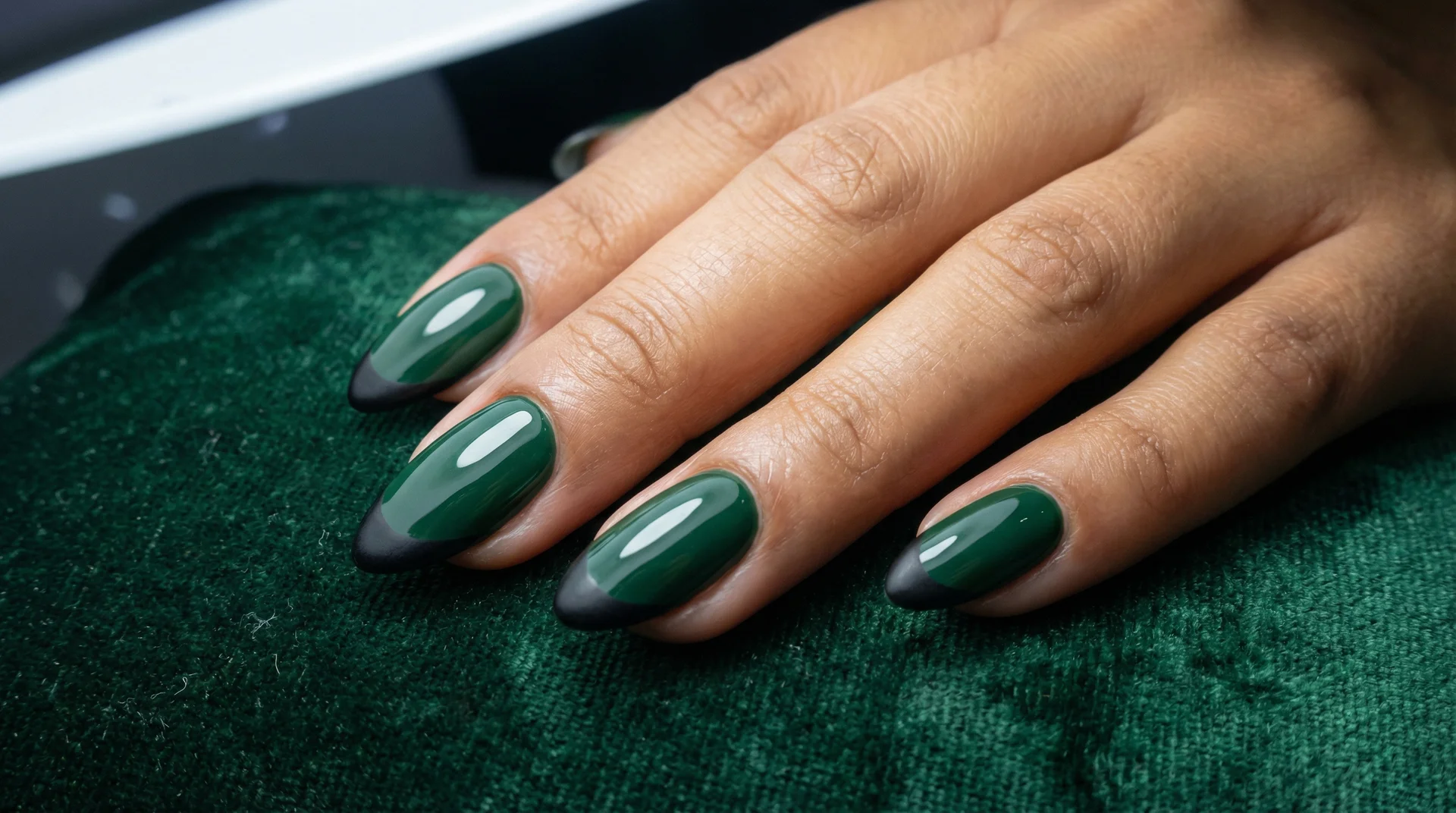 Almond nails with matte black french tip on deep forest green glossy base