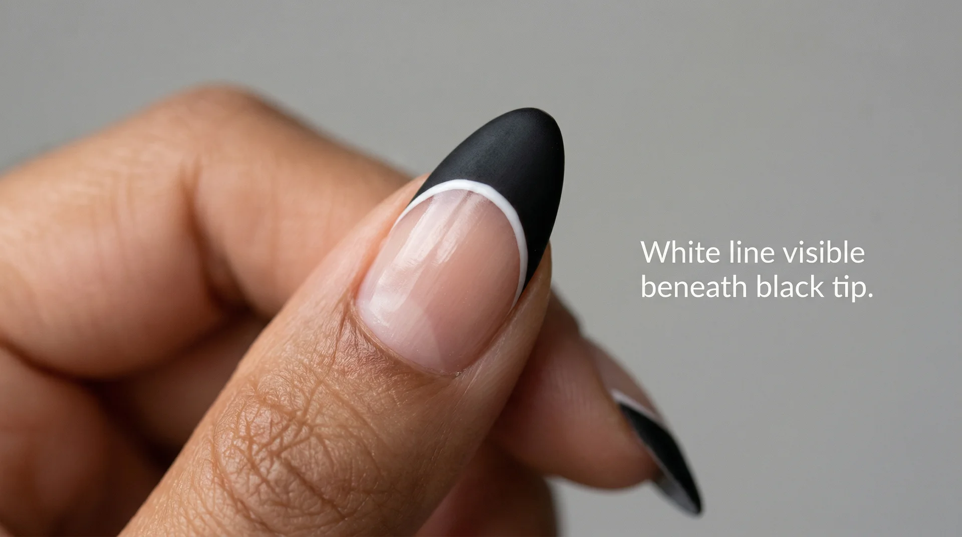 Double-layered french tip almond nails showing thin white line beneath a matte black tip