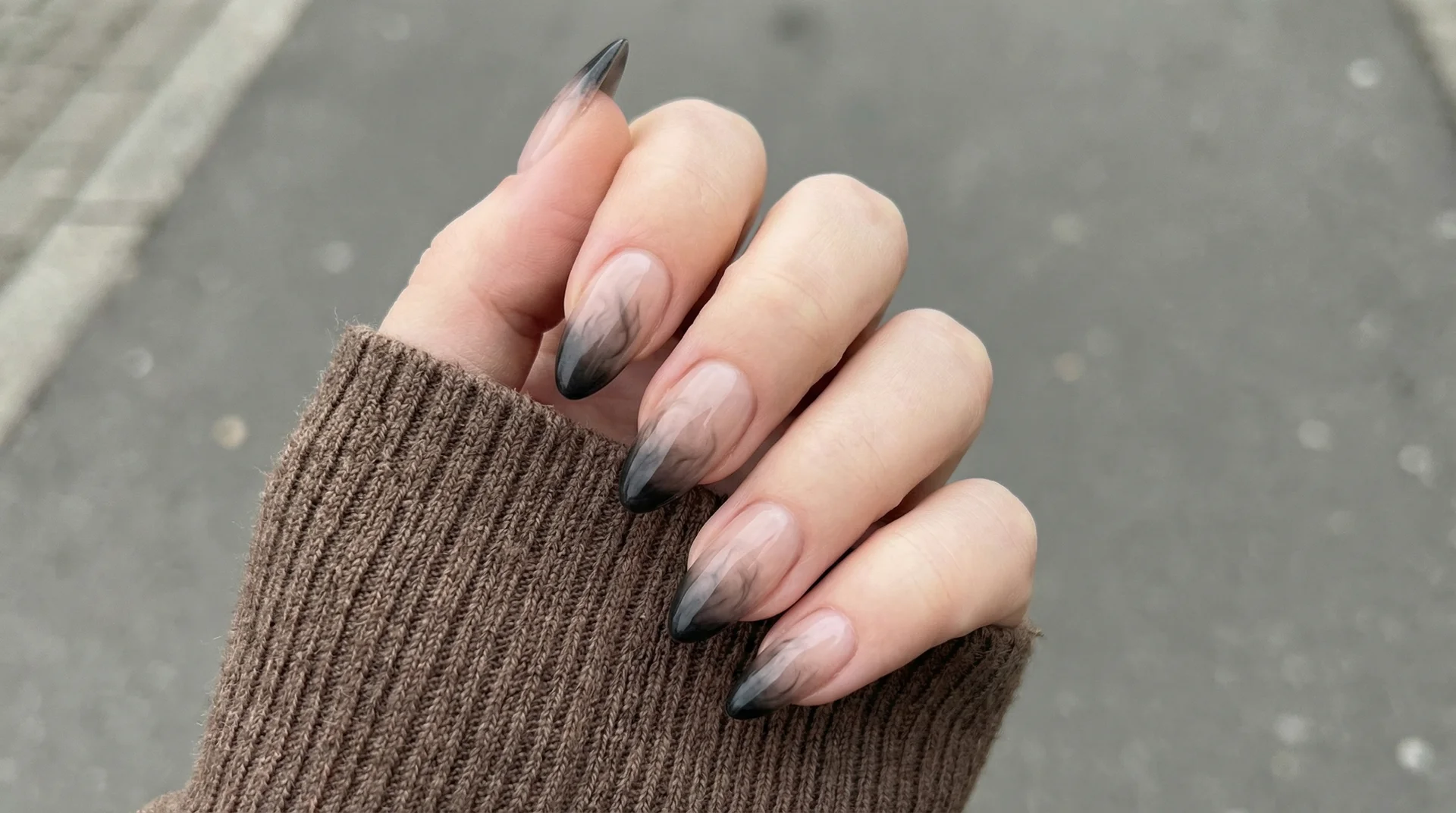 Long almond nails with seamless black smoke fade ombre tip blending into sheer natural base