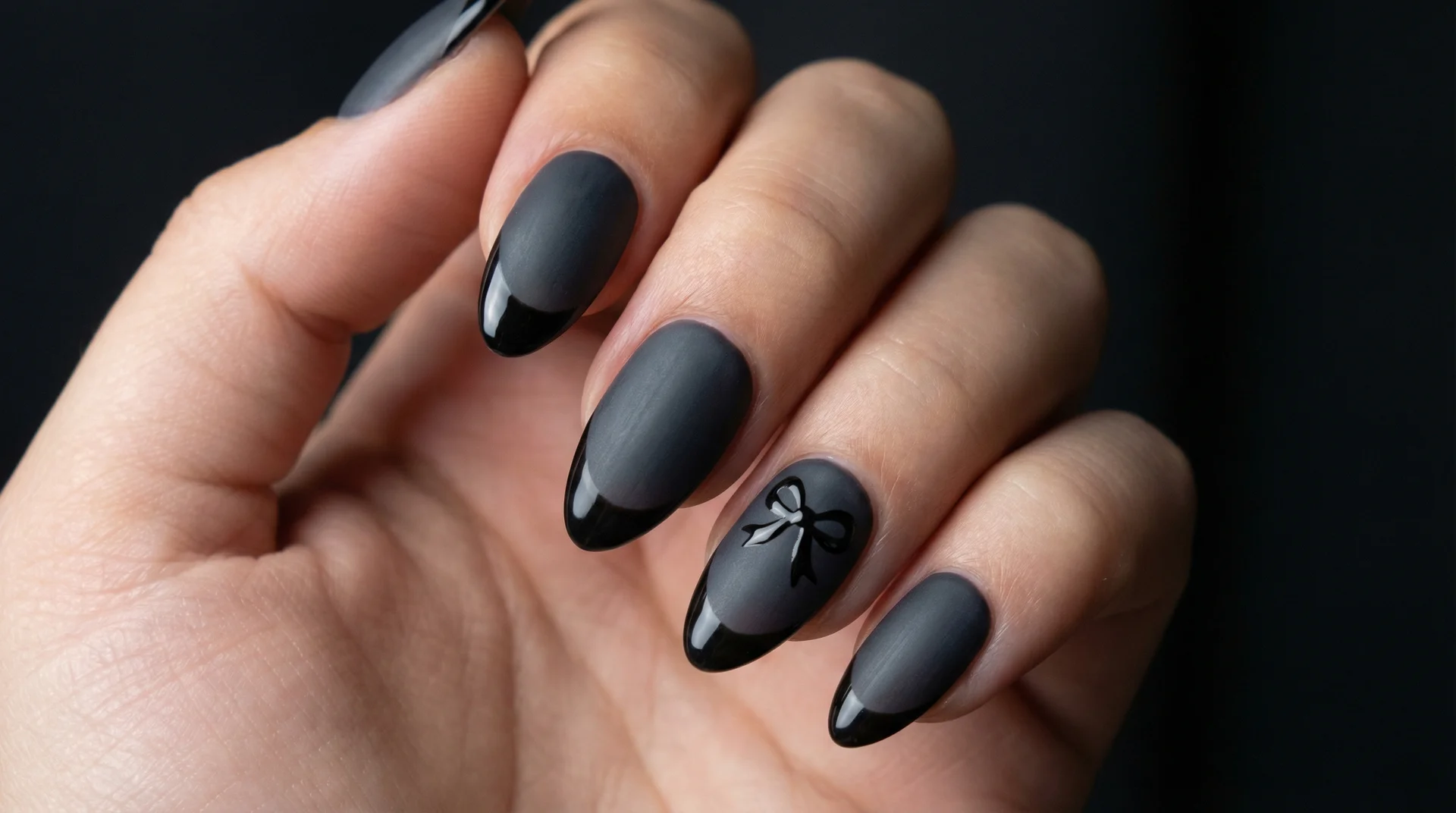 Wednesday Addams almond nails with charcoal base, glossy black tip, and tiny black bow accent