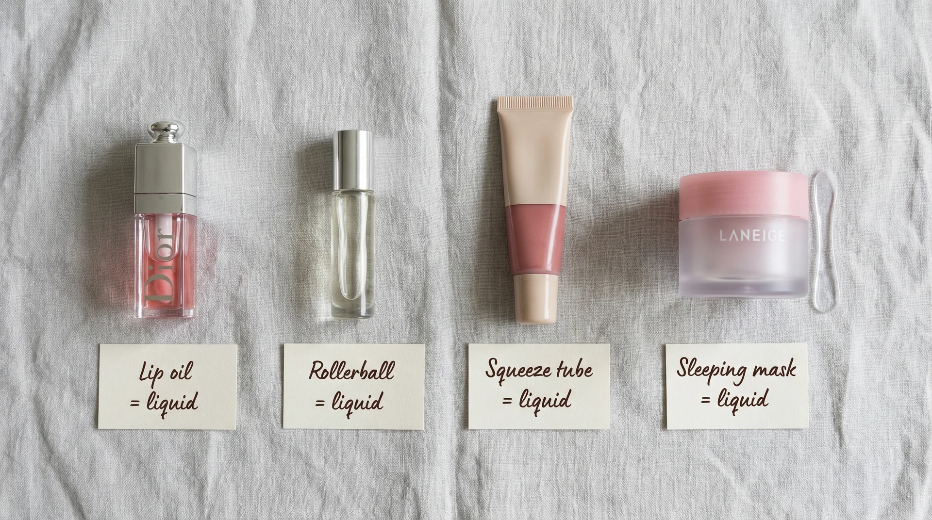 Lip oil, rollerball, squeeze tube balm, and lip sleeping mask pot labeled as TSA liquids in flat lay