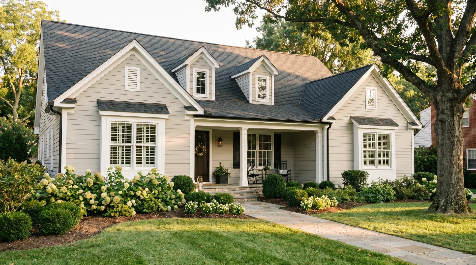 Home exterior in Agreeable Gray SW 7029 with white trim, black hardware, and charcoal shingles in afternoon light