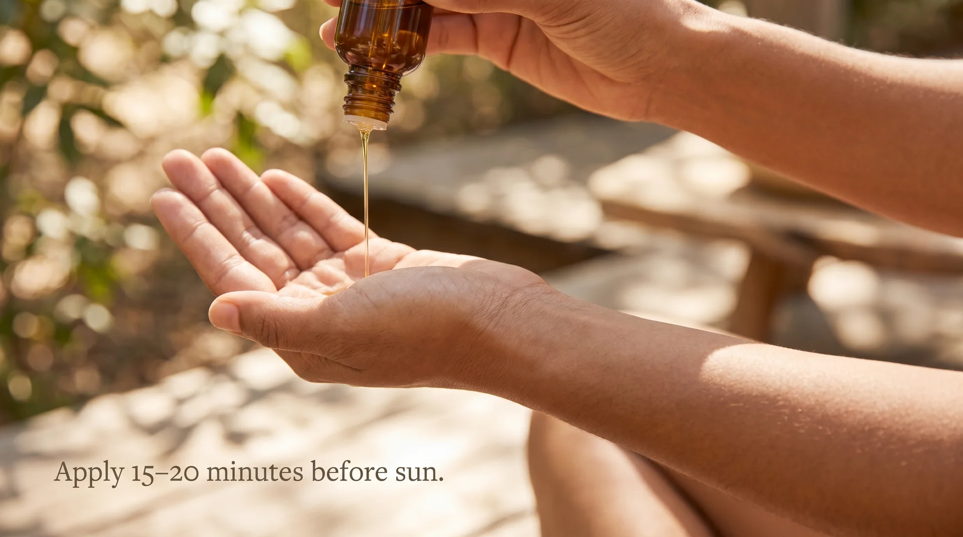 Pouring DIY tanning oil into hand before sun exposure, dark glass bottle against warm outdoor light