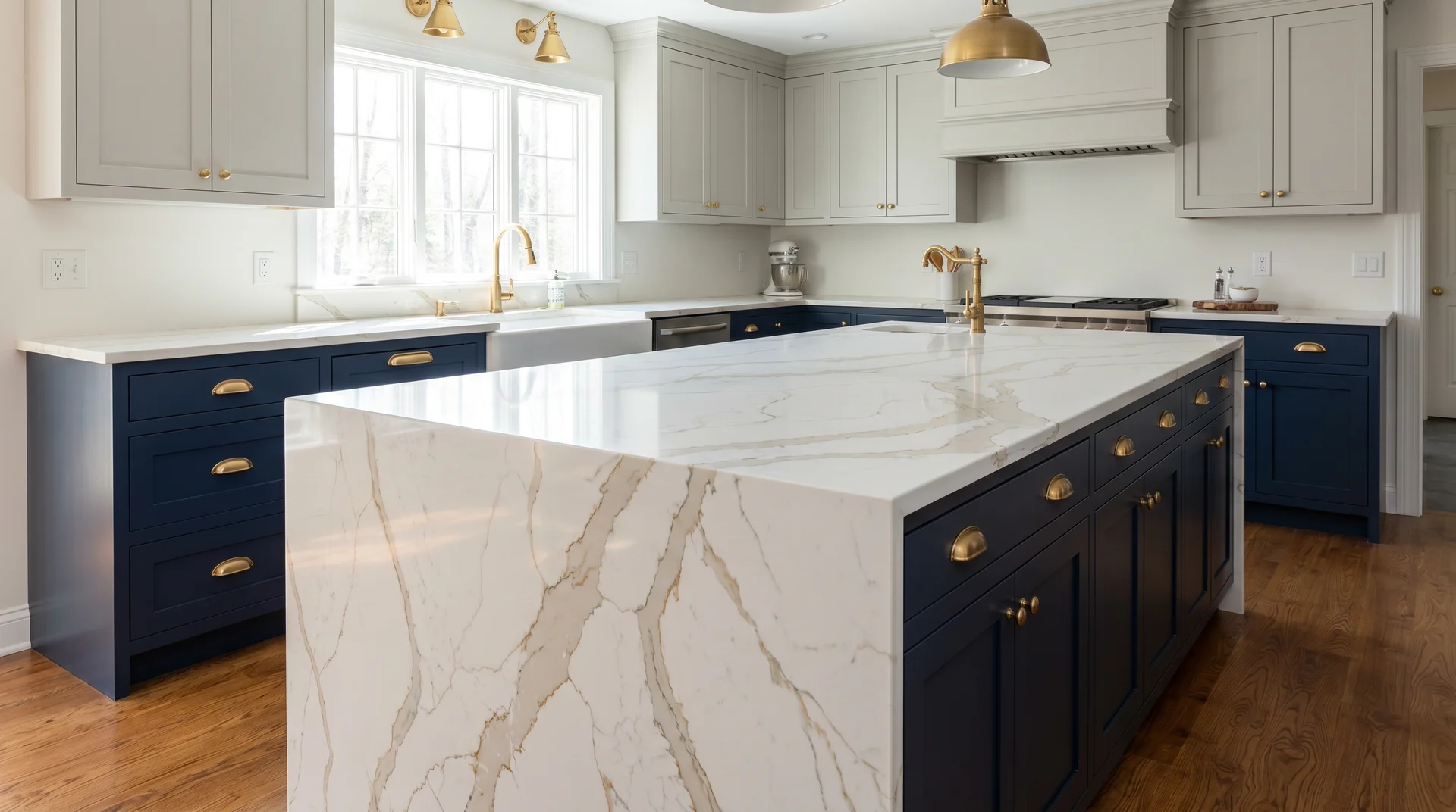 Two tone navy and gray kitchen where Calacatta quartz waterfall countertop is the visual focal point framed by cabinet colors 